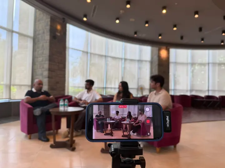 A phone on a tripod recording a podcast conversation in an ISB lounge