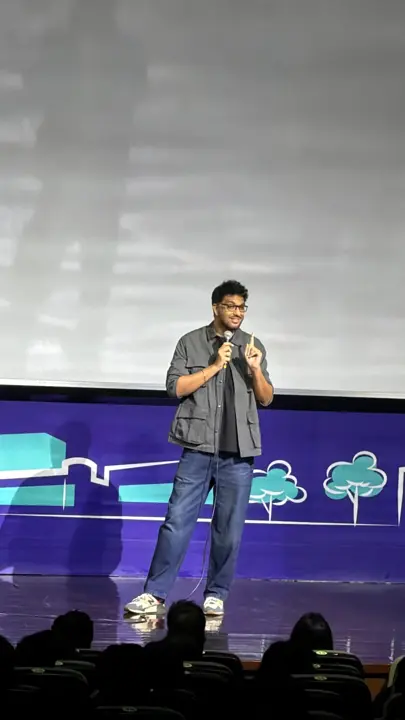 A stand-up comedian on the ISB stage holding a microphone
