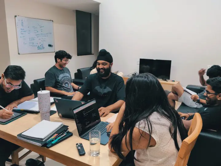 Classmates laughing around a table of laptops and notebooks during a study session